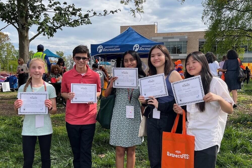 A group of five students holding up certificates