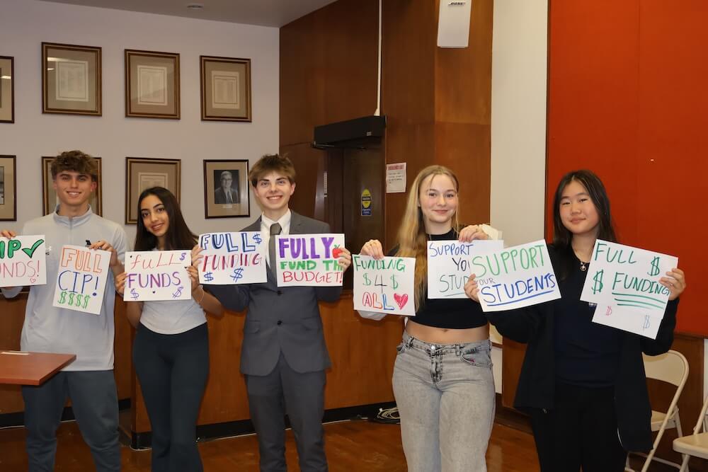 A group of SMOB Advisory Council students hold up advocacy signs to support fully funding the MCPS budget