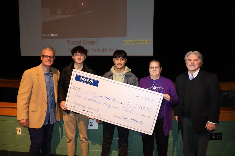 Two students hold up a check from the MCCPTA for winning the Speak Up, Save a Life PSA Contest