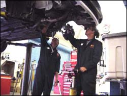 Students working on undercarriage of car